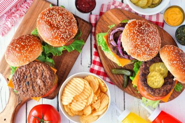 Barbekü hamburger masası sahnesi. Beyaz ahşap arka planda tepeden aşağı görünüm.