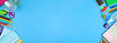 Okul malzemeleri ve COVID 19 önleyici madde. Mavi kağıt kaplamalı arka planda çifte sınır. Salgın konsepti sırasında okula dönmek.