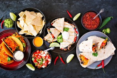 Meksika yemek masası sahnesi, arka planda üst görüntü. Taco, quesadilla, burrito ve nachos.