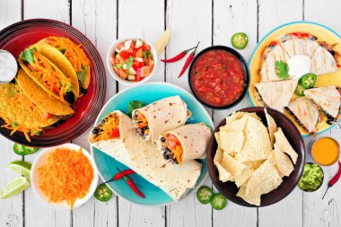 Meksika yemek masası sahnesi, beyaz ahşap arka planda üst manzara. Taco, burrito, quesadilla ve nachos.
