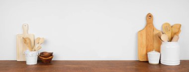Mutfak eşyaları ve mutfak gereçleri ahşap bir rafta ya da tezgahta. Beyaz duvara karşı fotokopi alanı olan pankart. Ev mutfağı yemek dekorasyonu.