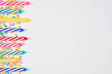 Çikolata parçacıklı renkli doğum günü pastası mumları. Beyaz arka planda, görüş sınırının üstünde. Boşluğu kopyala.