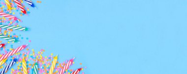 Şeker parçacıklı doğum günü pastası mumları. Mavi arka planda köşesi olan üst manzara afişi. Boşluğu kopyala.