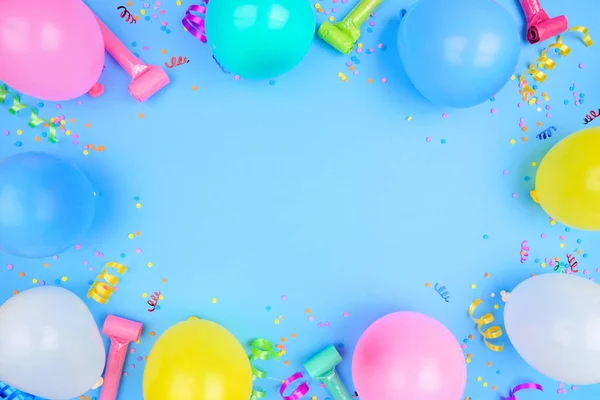 Birthday party theme frame on a blue background. Top down view with balloons, streamers and confetti. Copy space.