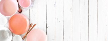 Pastel pembe, mercan, beyaz ve gri renklerde sofra takımı. Genel manzara, köşe kenarı beyaz ahşap pankartta. Boşluğu kopyala.