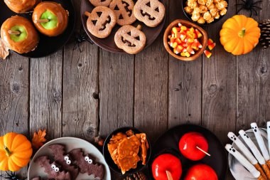 Köylü cadılar bayramı, karanlık ahşap zemin üzerinde fotokopi alanı olan iki sınırı tedavi ediyor. Yukarıdan aşağıya doğru. Karışık kurabiye, elma şekeri, şeker ve şeker..