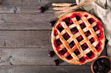 Fotokopi alanı olan ahşap bir zemine karşı vişneli turta masası sahnesi. Sonbahar yemekleri konsepti.
