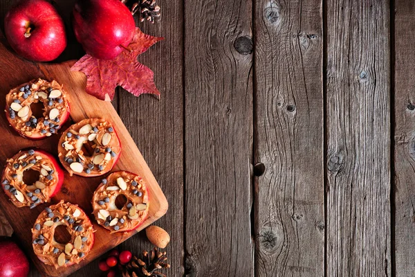 Peanut butter apple rounds. Top view side border on a rustic wood background with copy space. Autumn food concept.