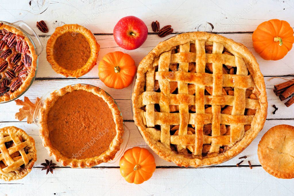 Assorted homemade autumn pies. Apple, pumpkin and pecan. Above view table scene on a white wood background.