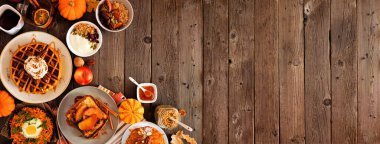 Sonbahar kahvaltısı ya da brunch malzemeleri çeşitleri. Karanlık ahşap bir arkaplan ile köşe sınırı. Kabak aromalı waffle, elmalı tost, yulaf ezmesi, yumurta tavası, yoğurt. Üst Manzara. Boşluğu kopyala.