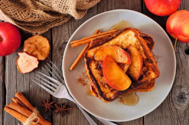 Karamelli tarçınlı Fransız tostu. Koyu bir ahşap arka planda, yukarıdaki masa manzarası. Sonbahar kahvaltısı kavramı.