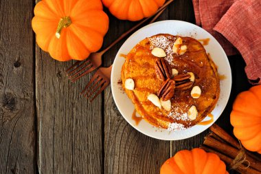Karamel soslu ve fındıklı balkabağı baharatlı krep. Masanın üstünde koyu ahşap bir arka plan ve fotokopi alanı var. Sonbahar kahvaltısı kavramı.