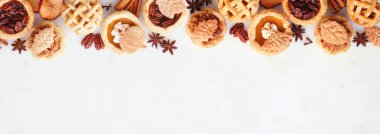 Sonbahar turtası temalı tatlı üst sınır. Beyaz mermer bir arkaplanla manzaranın üstünde. Balkabağı, elma ve cevizli mini turtalar..