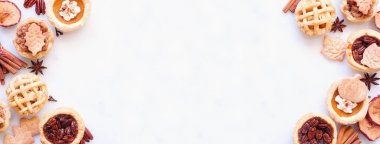 Sonbahar turtası temalı tatlı çifte sınır. Beyaz mermer pankartta yukarıdan bakıldığında. Balkabağı, elma ve cevizli mini turtalar..