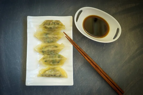 Asian dumplings in porcelain white ware on grey background.