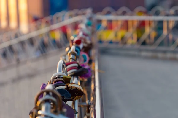 Background with lots of colorful locks on the bridge railing.