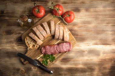 İtalyan ciabatta ekmeği Dilim salam ile Ahşap doğrama tahtası üzerinde kesti. Üstten Görünüm.