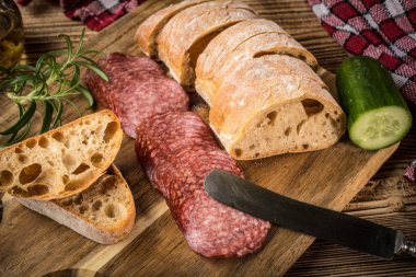 İtalyan ciabatta ekmeği Dilim salam ile Ahşap doğrama tahtası üzerinde kesilmiş.