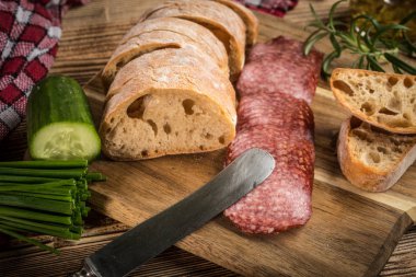 İtalyan ciabatta ekmeği Dilim salam ile Ahşap doğrama tahtası üzerinde kesilmiş.