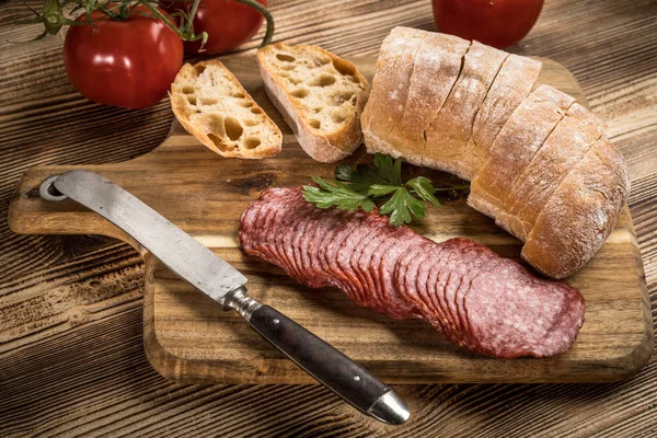 İtalyan ciabatta ekmeği Dilim salam ile Ahşap doğrama tahtası üzerinde kesilmiş.