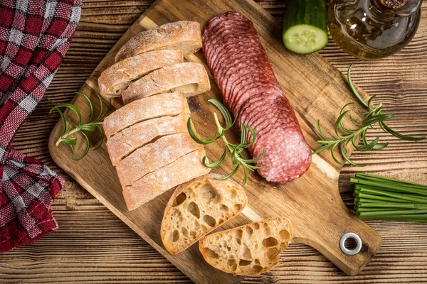 İtalyan ciabatta ekmeği Dilim salam ile Ahşap doğrama tahtası üzerinde kesilmiş.