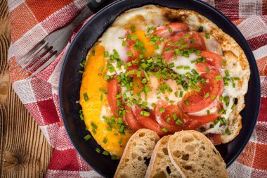 Ev yapımı kahvaltı yumurta ile domates ahşap masa üzerinde kızarmış. Üstten görünüm.