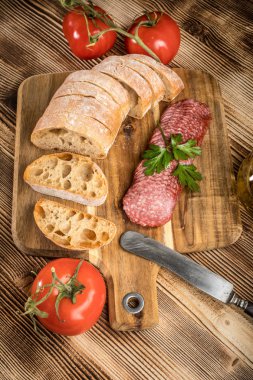 İtalyan ciabatta ekmeği Dilim salam ile Ahşap doğrama tahtası üzerinde kesilmiş.