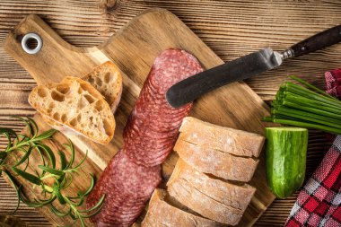 İtalyan ciabatta ekmeği Dilim salam ile Ahşap doğrama tahtası üzerinde kesilmiş.