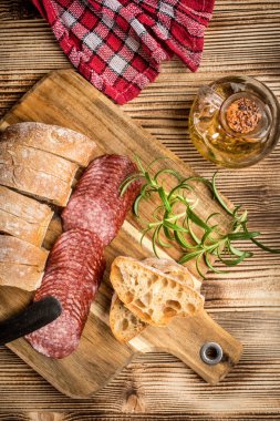 İtalyan ciabatta ekmeği Dilim salam ile Ahşap doğrama tahtası üzerinde kesilmiş.
