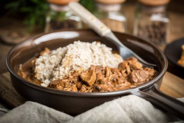 Bir tavada pişirilmiş etli arpa kabuğu çıkarılmış tane servis.