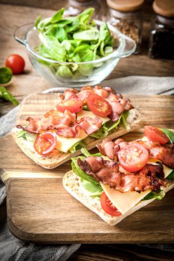 Ahşap tahta üzerinde Roka Salatası, pastırma ve sarı peynirli ciabatta sandviç.