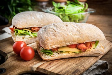 Ahşap tahta üzerinde Roka Salatası, pastırma ve sarı peynirli ciabatta sandviç.