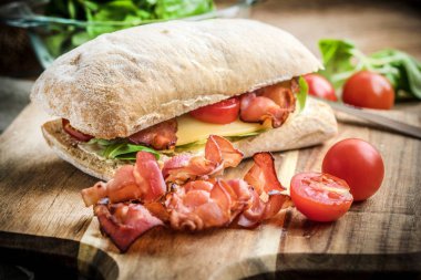 Ahşap tahta üzerinde Roka Salatası, pastırma ve sarı peynirli ciabatta sandviç.
