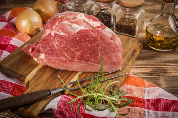 Raw pork shoulder on cutting board with knife.