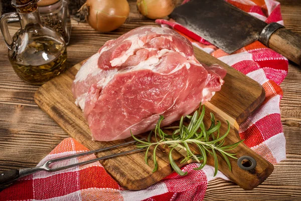 Raw pork shoulder on cutting board with knife.