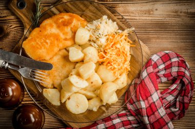 Kızarmış tavuk göğsü haşlanmış patates ve salata ile servis.