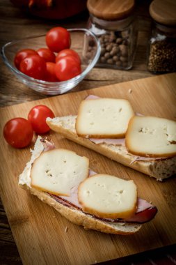 Jambon ve kesme tahtası üzerinde füme peynir sandviç.