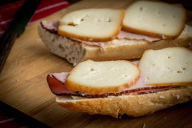 Jambon ve kesme tahtası üzerinde füme peynir sandviç.