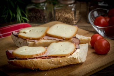 Jambon ve kesme tahtası üzerinde füme peynir sandviç.