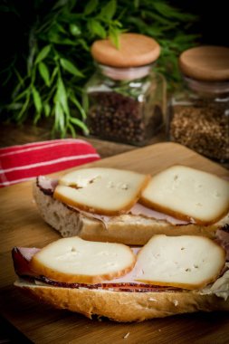 Jambon ve kesme tahtası üzerinde füme peynir sandviç.