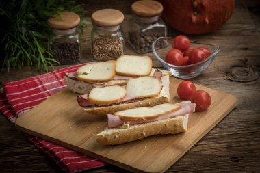 Jambon ve kesme tahtası üzerinde füme peynir sandviç.