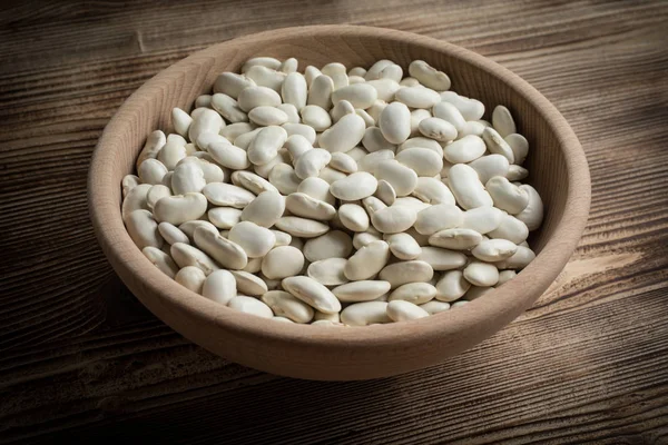 Dried white beans in a wooden bowl.