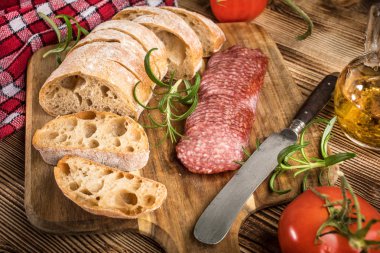 İtalyan ciabatta ekmeği Dilim salam ile Ahşap doğrama tahtası üzerinde kesilmiş.