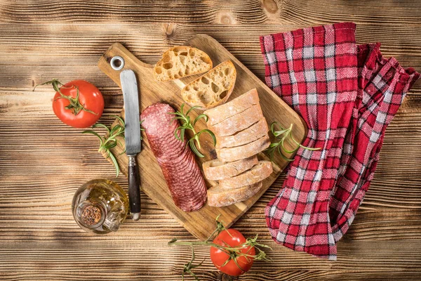 İtalyan ciabatta ekmeği Dilim salam ile Ahşap doğrama tahtası üzerinde kesilmiş.