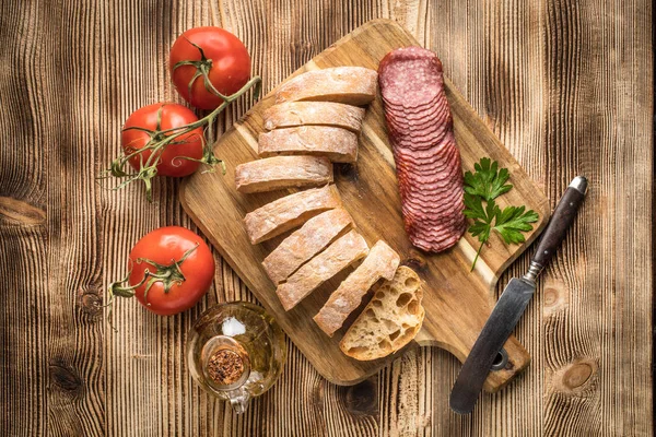 İtalyan ciabatta ekmeği Dilim salam ile Ahşap doğrama tahtası üzerinde kesti. Üstten Görünüm.