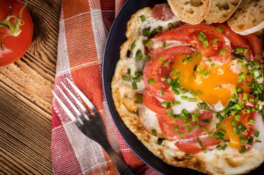 Ev yapımı kahvaltı yumurta ile domates ahşap masa üzerinde kızarmış. Üstten görünüm.