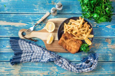 Tabakta patates kızartması olan kızarmış morina balığı. Üst görünüm.