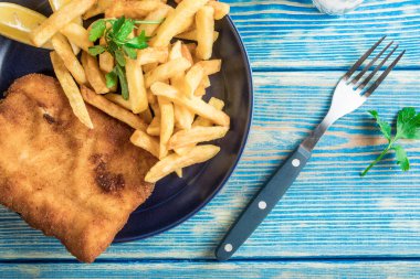 Tabakta patates kızartması olan kızarmış morina balığı. Üst görünüm.