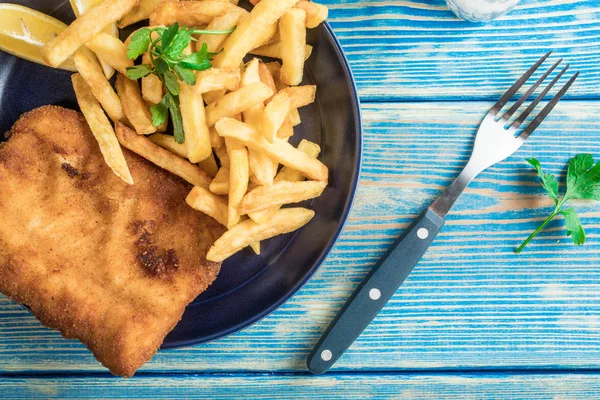 Tabakta patates kızartması olan kızarmış morina balığı. Üst görünüm.