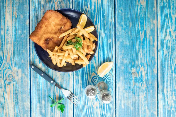 Tabakta patates kızartması olan kızarmış morina balığı. Üst görünüm.